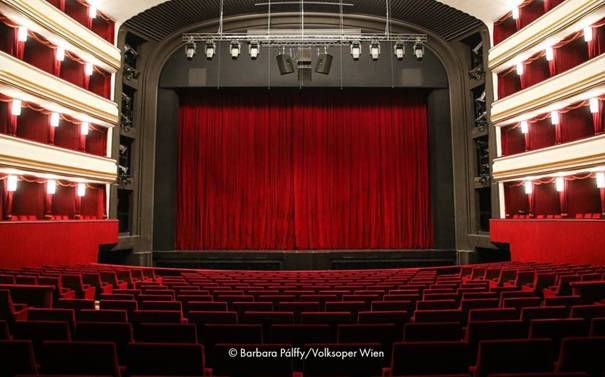 A photo of an inside of a theatre with red curtains.